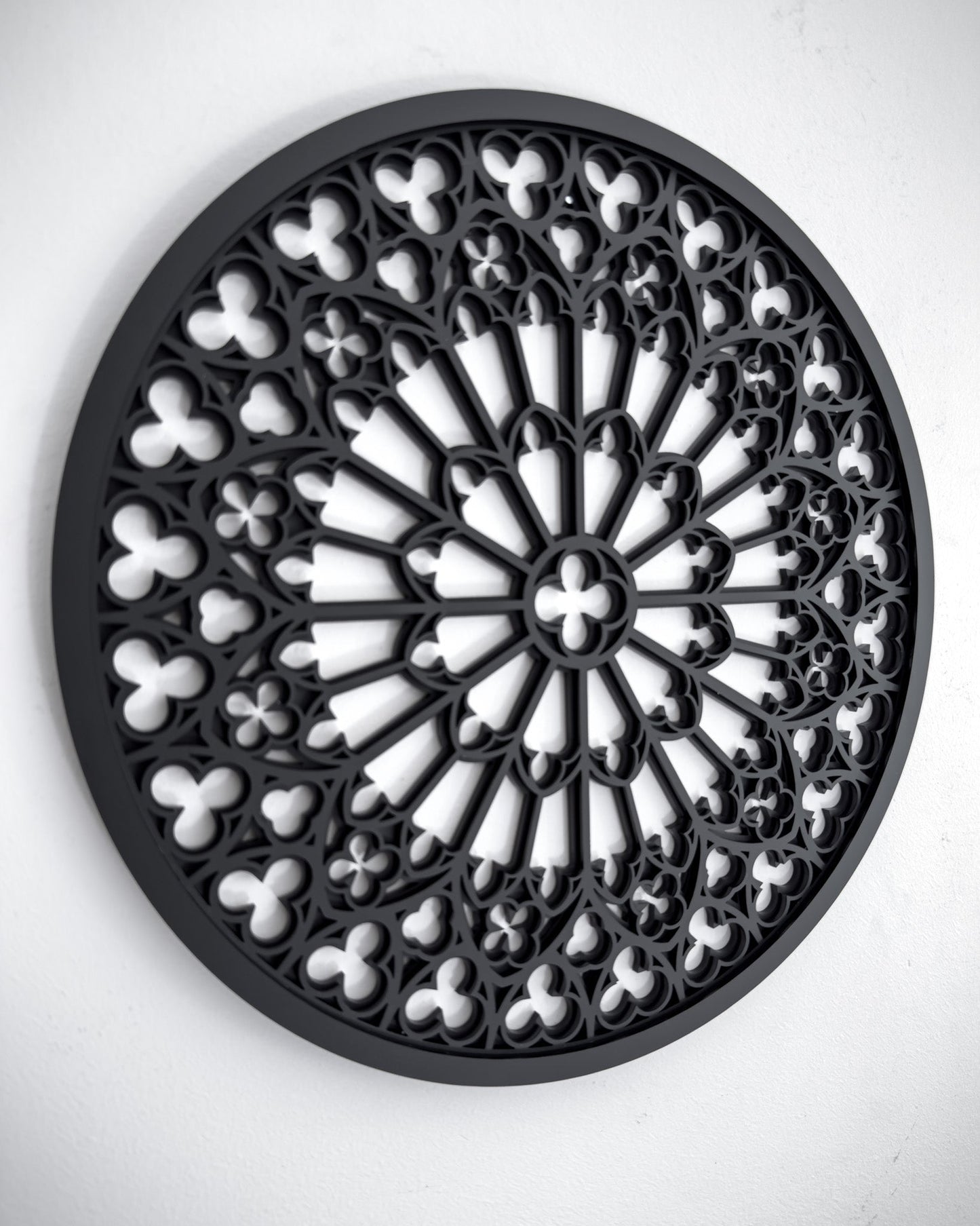 Side view of Notre Dame cathedral rose window tracery wall art in black layered acrylic on a white wall