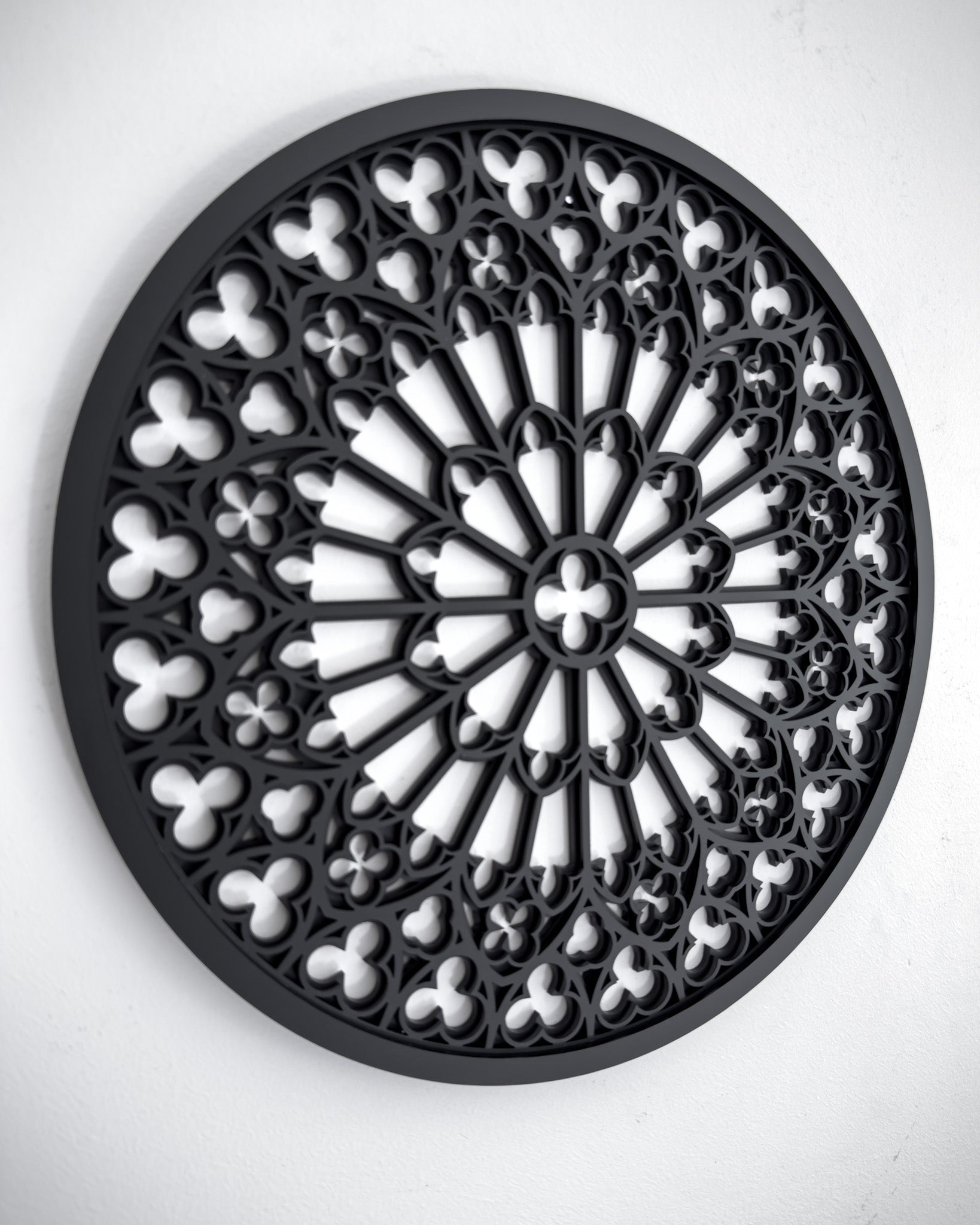 Side view of Notre Dame cathedral rose window tracery wall art in black layered acrylic on a white wall