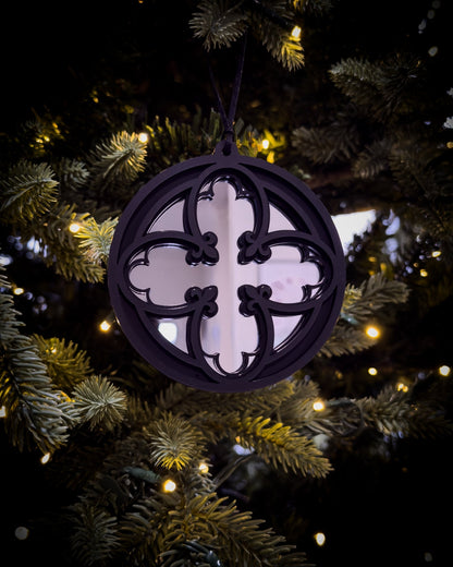 Silver gothic cathedral quatrefoil ornament hanging on Christmas tree with warm lights