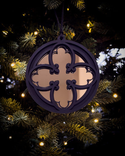 Gold gothic cathedral quatrefoil ornament hanging on Christmas tree with warm lights