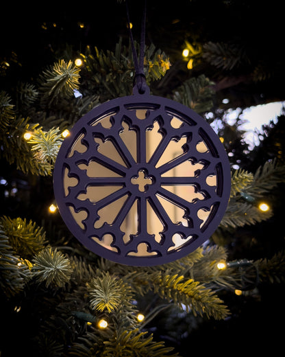 Gold gothic cathedral rose window ornament hanging on Christmas tree with warm lights