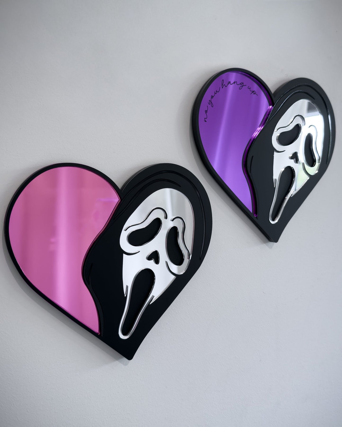 Ghostface heart mirrors in pink and purple acrylic mounted on a white wall