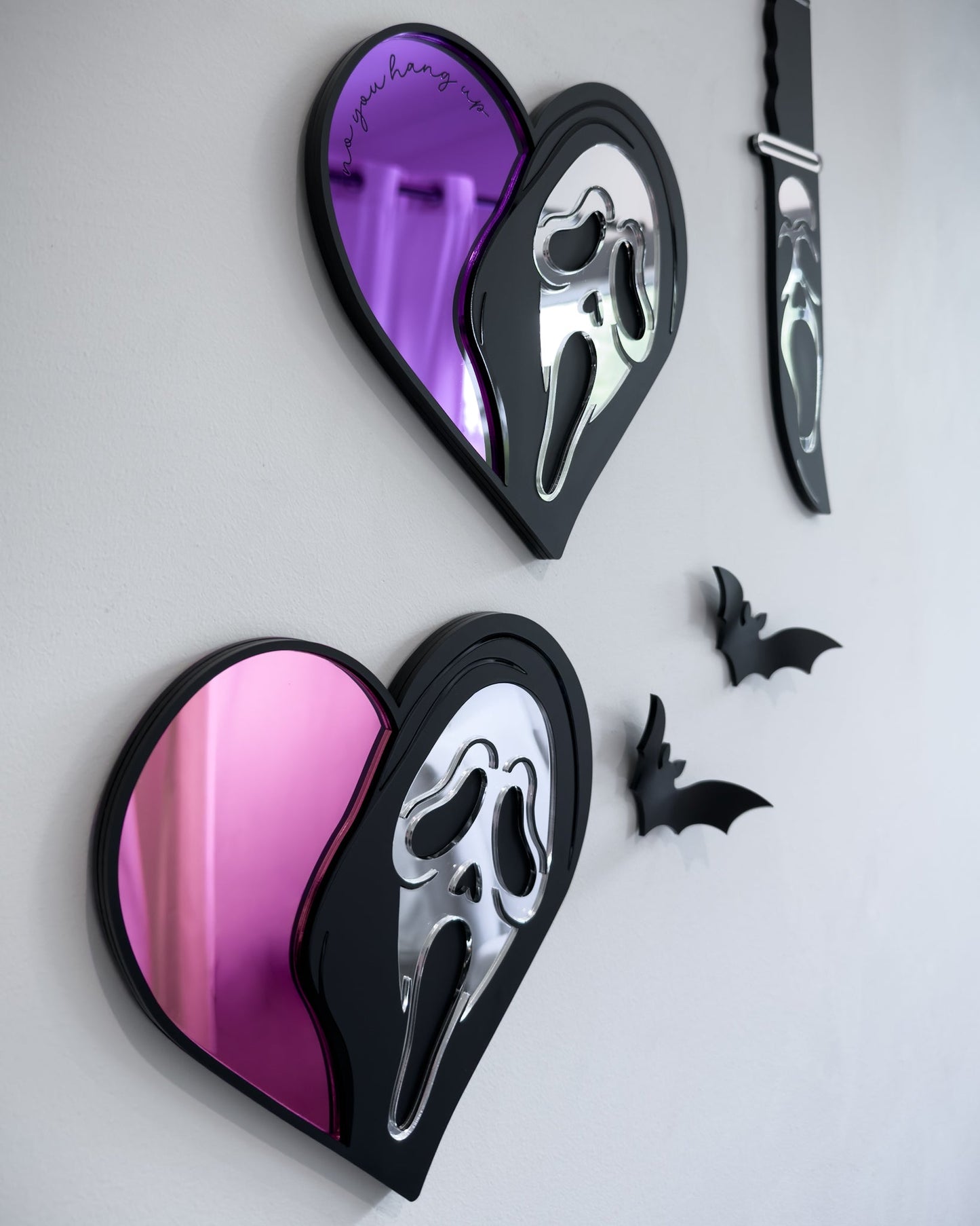 Side view of slasher heart mirror wall art with Ghostface mask design in pink and purple acrylic on a white wall