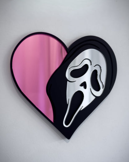 Pink Ghostface heart mirror in black acrylic mounted on a white wall