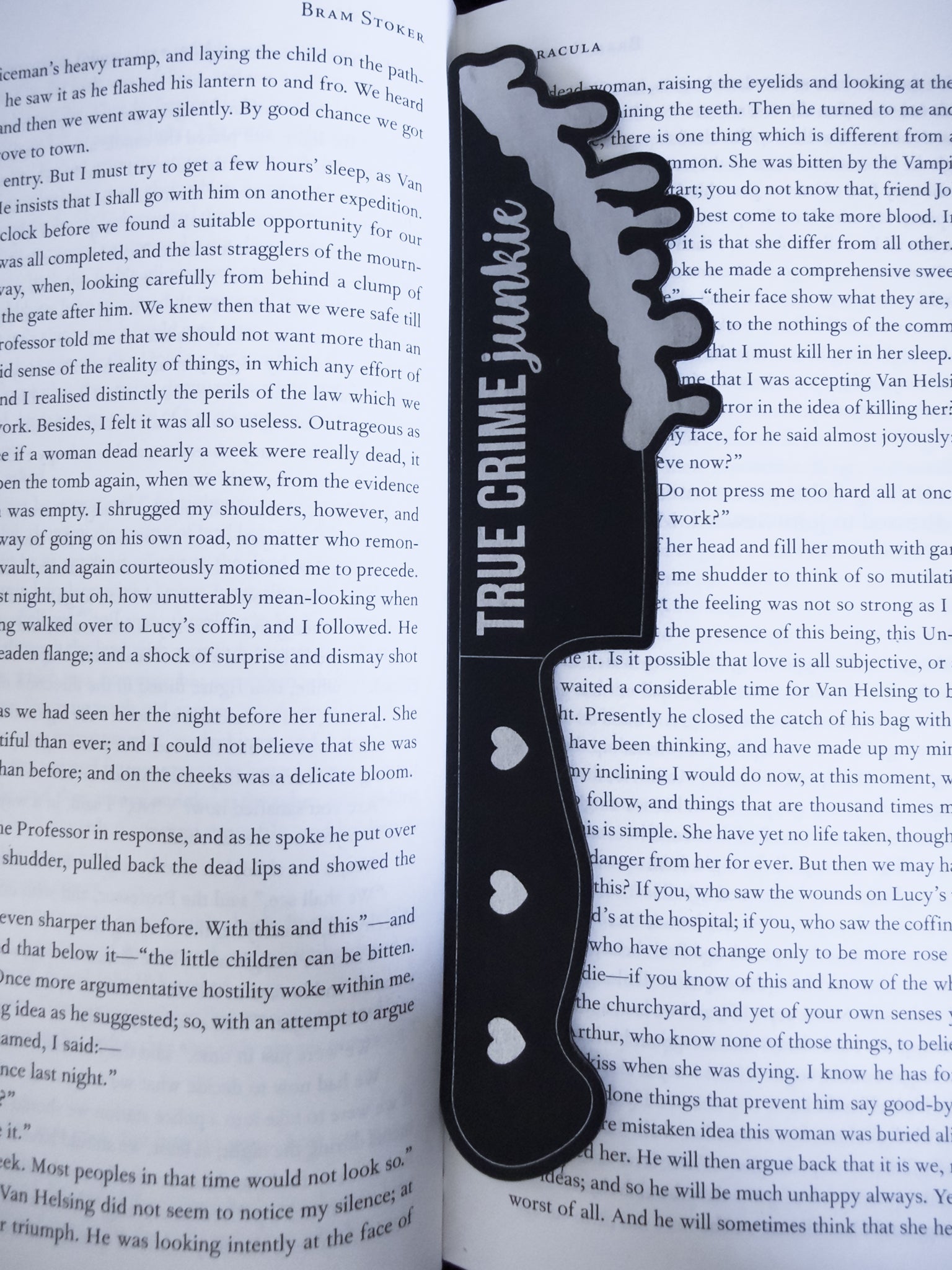True crime junkie knife bookmark in black and silver  leatherette resting on an open book